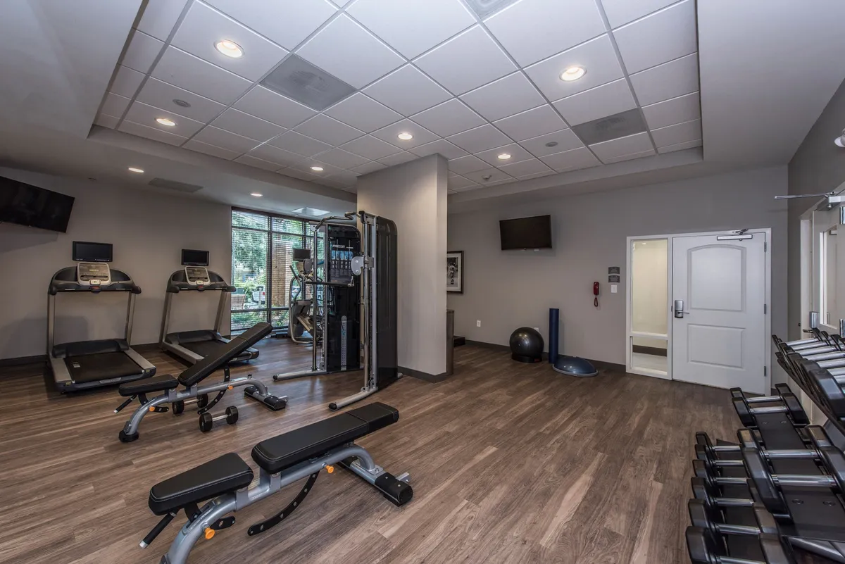 A contemporary fitness center equipped with treadmills, a weight bench, a multi-gym machine, and an exercise ball. The space is bright and motivational, designed for both personal workouts and group fitness classes, emphasizing wellness and active living for guests.