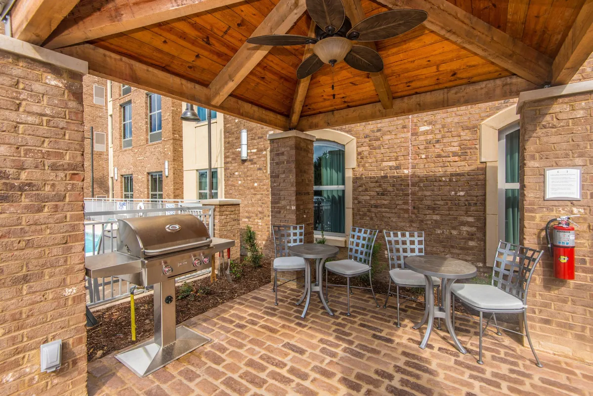 A well-appointed exterior space featuring a barbecue grill, ample seating, and a wooden ceiling, ideal for outdoor dining and socializing. The layout encourages guests to gather, enjoy freshly grilled meals, and celebrate special occasions in a casual, friendly setting.